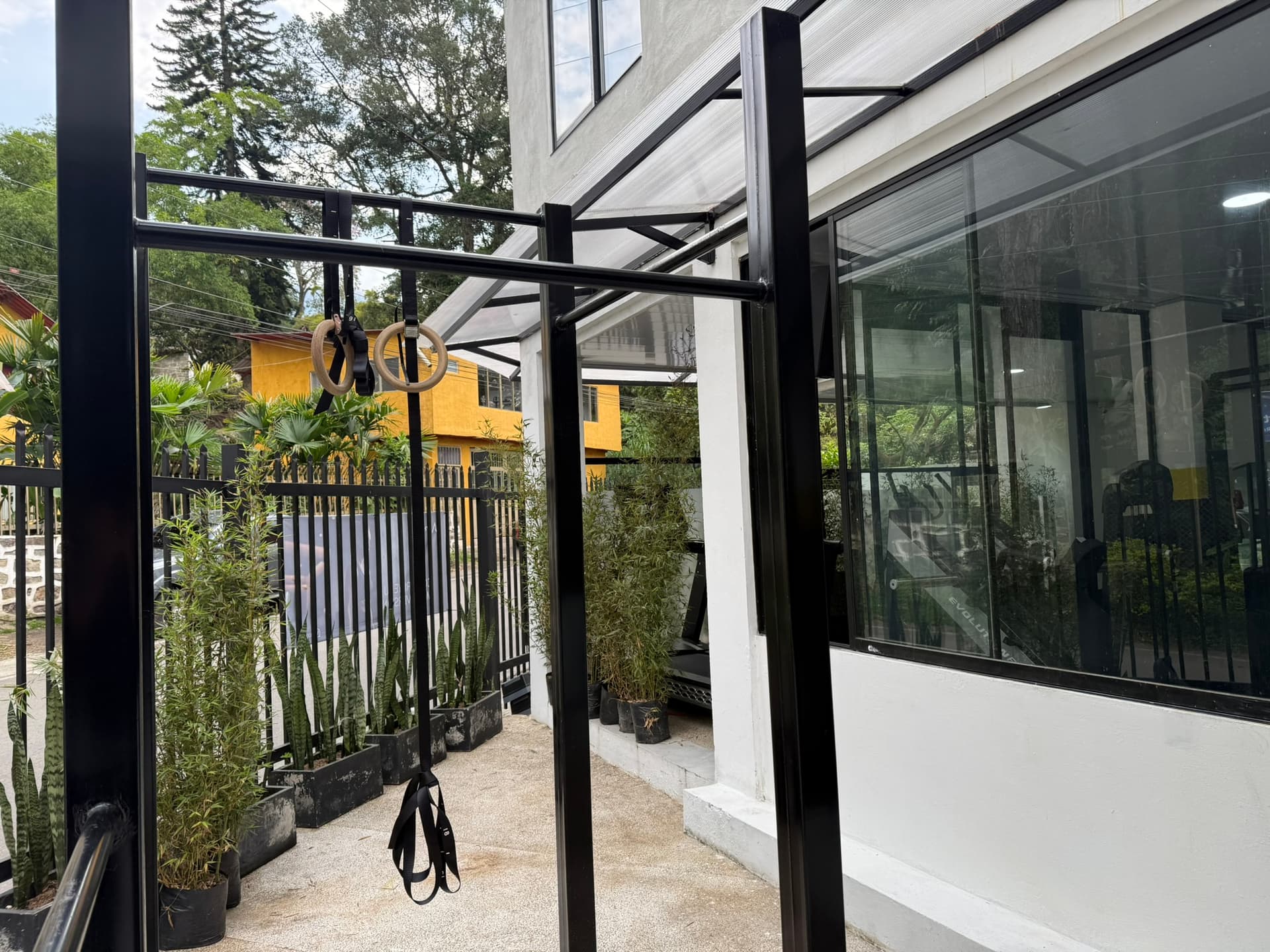 ATHOS outdoor calisthenics rig with rings and TRX among the plants