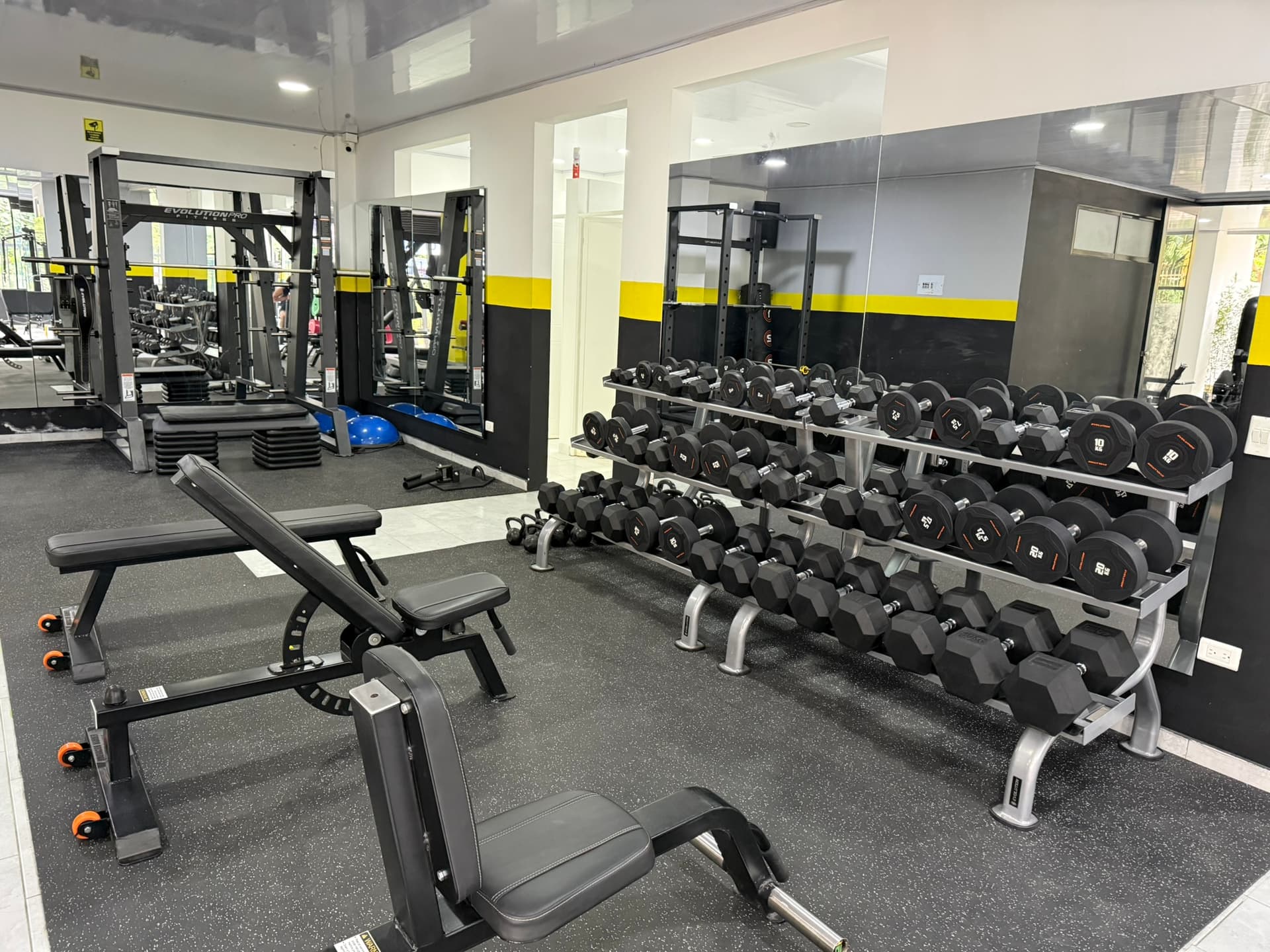 Inside ATHOS Gym: the free-weight floor with dumbbells and a Smith machine